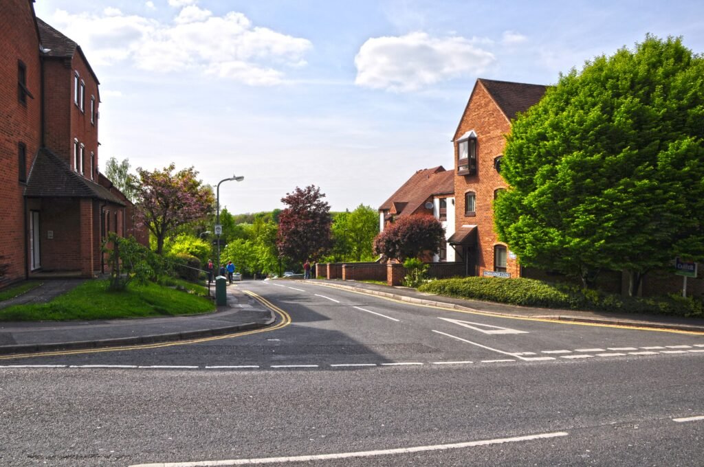 Commainge Close in Warwick, a road between red-brick flats leading down from Theatre Street, with a blue parking sign by the pavement