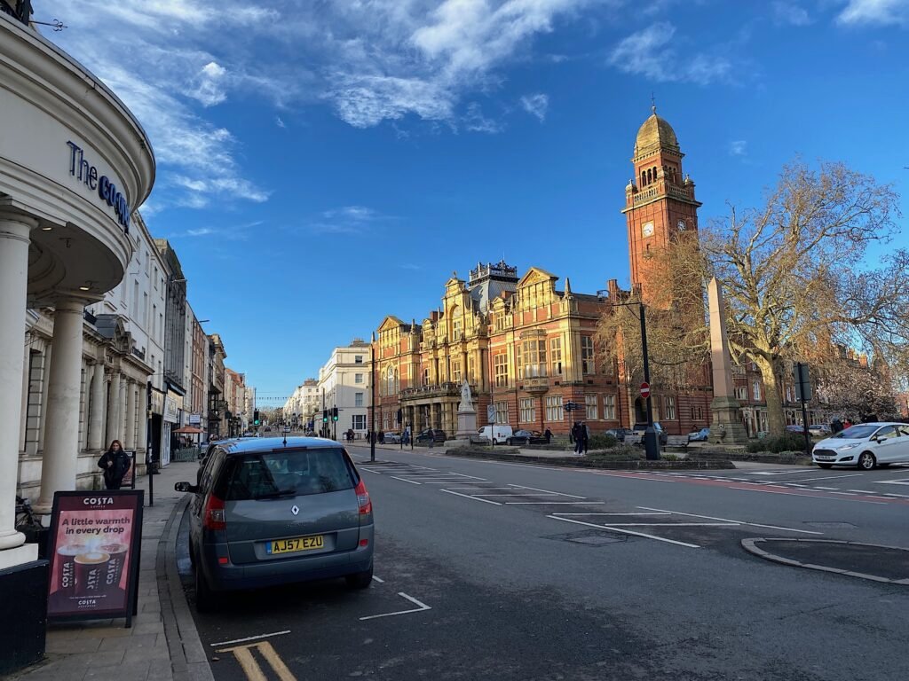 Leamington Spa Town Hall's red-brick clock tower and the Parade under a blue sky, with Queen Victoria's statue in front