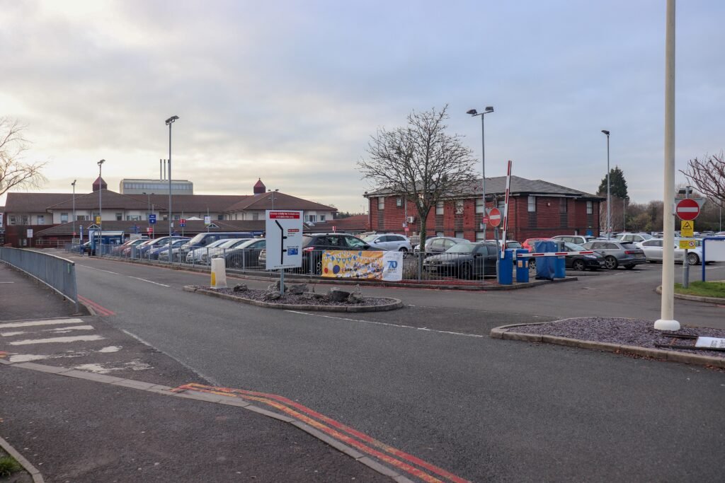 Warwick Hospital's red-brick buildings beside a visitor car park on Lakin Road, Warwick, on a grey winter afternoon